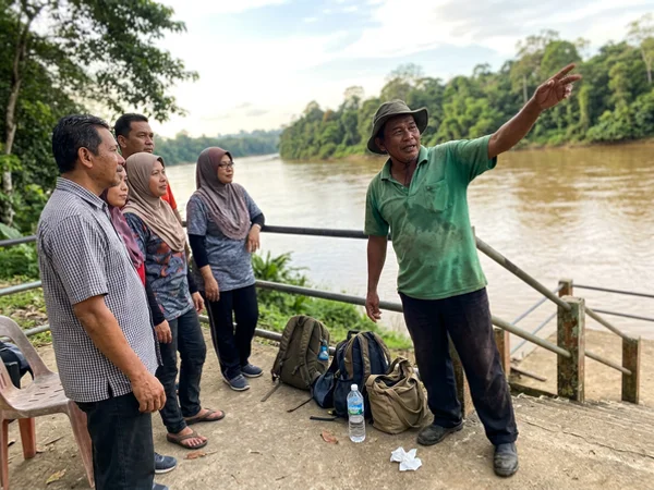 A guide and small private group at a riverside viewpoint over the Tembeling